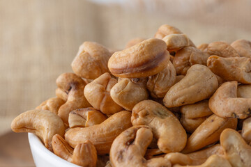 Roasted cashew nuts and halves in wooden bowl on table top view. Macro studio shot Homemade Roasted Salted Cashews in basket and spoon breakfast on sack, Healthy food Seeds snack product
