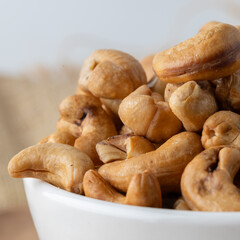 Roasted cashew nuts and halves in wooden bowl on table top view. Macro studio shot Homemade Roasted Salted Cashews in basket and spoon breakfast on sack, Healthy food Seeds snack product