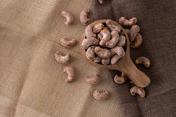 Fototapeta na wymiar Roasted cashew nuts and halves in wooden bowl on table top view. Macro studio shot Homemade Roasted Salted Cashews in basket and spoon breakfast on sack, Healthy food Seeds snack product