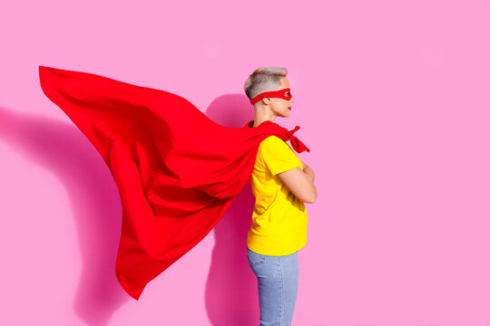 Profile photo of cool superhero girl folded arms look empty space flying red cape isolated on pink color background