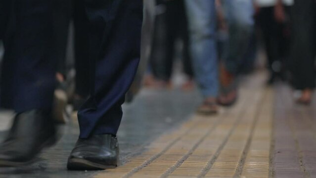 Shoes and legs of commuting train passengers at busy railway station in Mumbai, India.