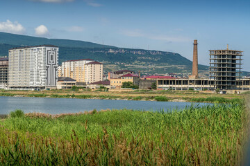 The shore of Akgel lake in the summer, in the outskirts of Mahachkala, Dagestan Republic, Southern Russia with the newly constructed buildings, old factory and building under construction