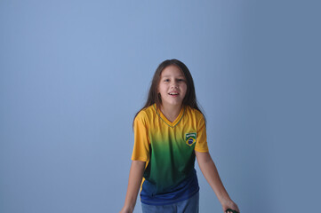 menina sorridente usando camisa do brasil em fundo azul 