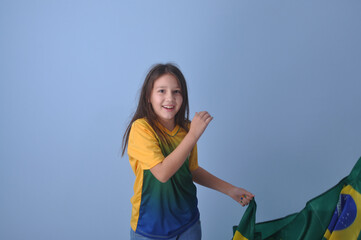 menina sorridente usando camisa do brasil em fundo azul 