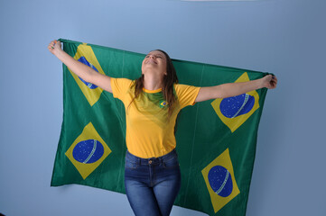 mulher brasileira segurando bandeira do brasil em fundo azul, celebração da nação brasileira 