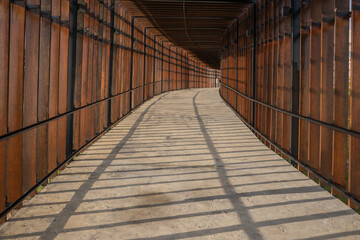 An inviting perspective of a wooden walkway, leading the eye on an uncharted journey towards a point in the distance