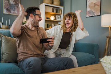 couple man and woman husband wife play smart phone video games at home