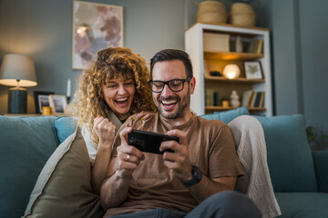 couple man and woman husband wife play smart phone video games at home