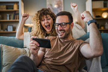 couple man and woman husband wife play smart phone video games at home