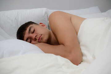 Fototapeta na wymiar Shirtless Young Man Sleeping in Bed