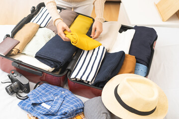 Travel concept, happy asian young woman hand preparing packing luggage bag for summer vacation trip...