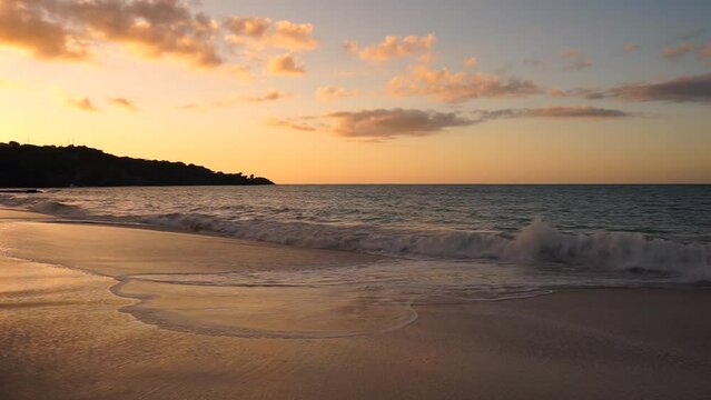 Golden sunset over Caribbean beach with waves lapping the shore. NO audio.