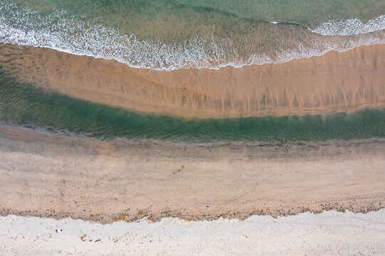 Aerial view of an empty beach with waves rolling on the shoreline in Vila do Conde, Porto, Portugal.