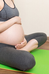 Beautiful pregnant woman doing yoga at home. Pregnancy Yoga and Fitness concept at coronavirus time