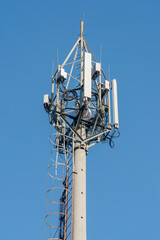 Communication transmitters on a concrete pole against the blue sky.