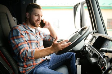 Young professional driver communicating over mobile phone while driving a truck.
