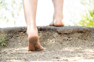 Men's bare feet climb the mountain to the top in the summer in the sun, go to the top, feet