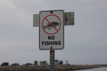 No Fishing sign at edge of lake on overcast day