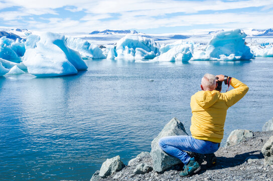 Middle-aged man traveler photographing icebergs in vatnajokull blue lagoon