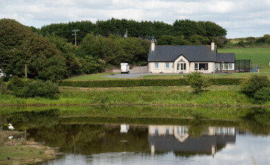 Fototapeta na wymiar Traditional countryside house in nature reflect in a lake. Peaceful lifestyle outdoor