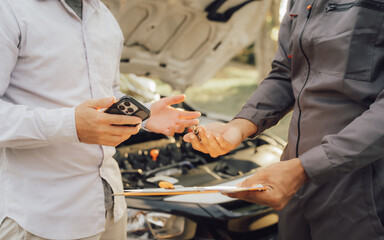 Young mechanic opens the bonnet to inspect the engine for damage and does professional maintenance. He puts on his uniform and inspects.	