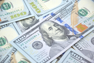 A pile of one hundred US banknotes with president portraits.