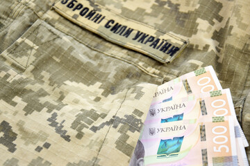 Ukrainian hryvnia against the background of a military pixel with the inscription of the armed...
