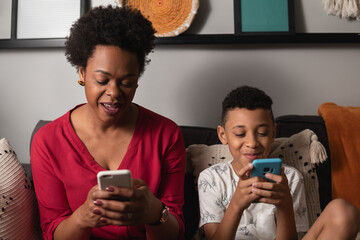 Mother and young son use cellphone together in living room at home