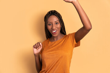 excited black woman raising arms and celebrating in all beige colors. celebration, positive, success concept.