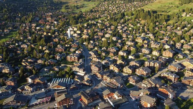 Verbier, Switzerland: Aerial drone footage of the famous Verbier mountain village with luxury chalets and the modern church in the Swiss alps in summer. 