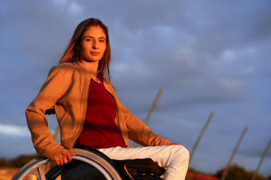 Portrait Of Person In Physical Disability. Confident Woman In Wheelchair Looking At Camera Outdoors In Park