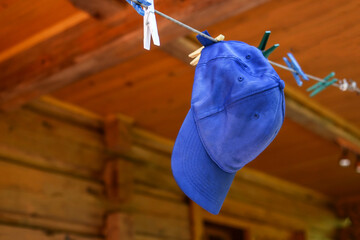 A blue cap for a boy hangs on a rope on the terrace. clean washed clothes.