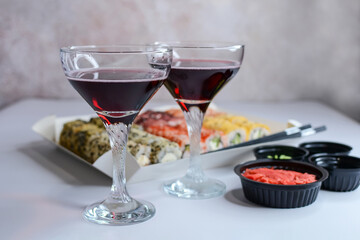 Holiday concept. Glasses with red wine, sushi and spices for sushi on the table on an abstract background