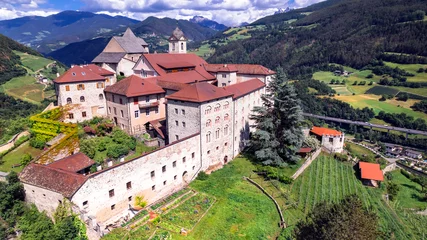 Poster Italy travel and landmarks .Scenic village Chiusa and it's famous benedictine monastery Sabiona in South Tyrol region , Bolzano province. Aerial drone view © Freesurf