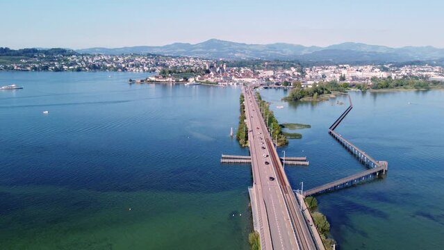 Rapperswil, Switzerland: Aerial drone footage of the bridge over Lake Zurich toward the rapperswil-Jona city in canton Saint Gallen on the sunny summer day with a forward motion. 