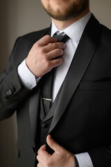 A man in a business suit puts on and straightens his tie with a clip. Wedding day concept,fashion, business, male style.