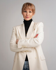 An attractive blond haired woman wearing white blazer and black sweater against isolated background