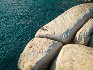 February 5, 2023 - Thailand: Aerial view of person on granite boulder about to jump into sea at Tanote bay, Ko Tao, Thailand.