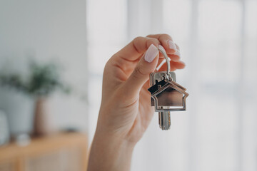 Woman holds house keys, symbolizing new home. Real estate agent offers apartments for sale or rent. Mortgage advertisement.