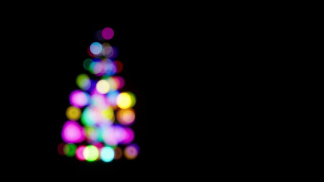  blurred christmas tree animation on black backgorund. Colorful decoration balls with glowing lights for ohliday theme concept card