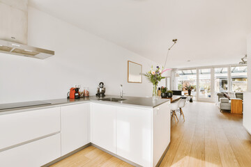 a kitchen and dining area in a house with wood flooring, white cabinets and stainless appliances on the wall
