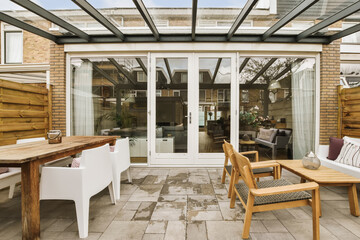 a patio with chairs, tables and an umbrella over the door that leads to a covered area for outdoor dining