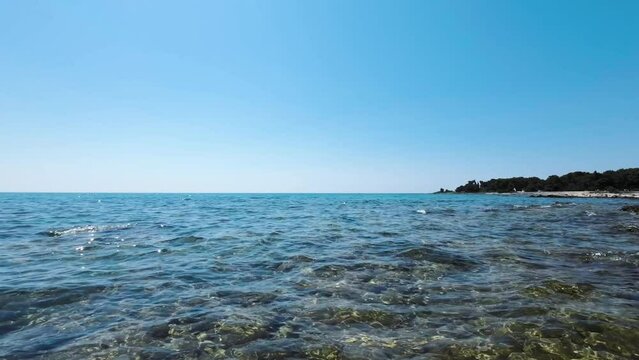 Crystal clear sea water in Umag, Croatia. Half underwater view of rock bottom and shore