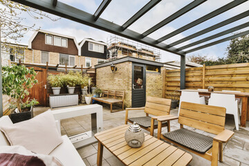 an outdoor living area with wooden furniture and plants on the side wall, including white sofas and coffee tables