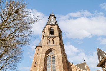 an old building with a clock on it's side and a tree in the fore - eyed area behind