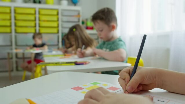 A close-up of the hands of a schoolboy drawing in a notebook. Teaching children at school in the classroom during the lesson, performing the teacher's tasks. High quality 4k footage