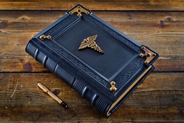 Blue leather book with Caduceus symbol lay down to wooden table