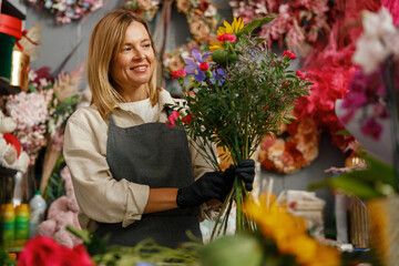 Female decorator creating beautiful bouquet at table. Lifestyle flower shop