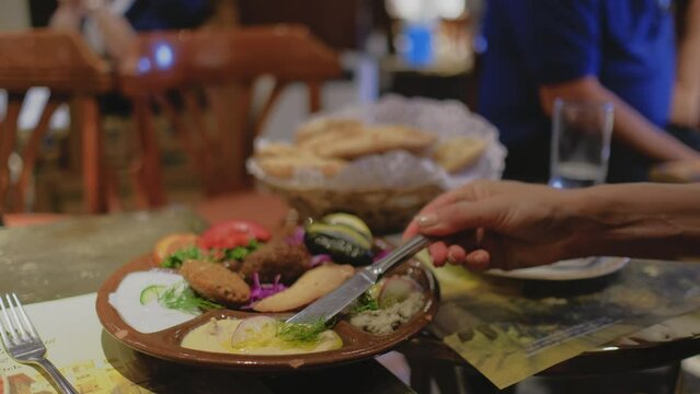 Egyptian food is on a table. Female hand putting a sauce on a bread. 