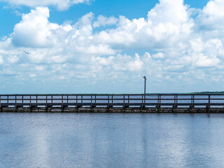 Obraz premium A long pier with beautiful clouds and bird in the distance